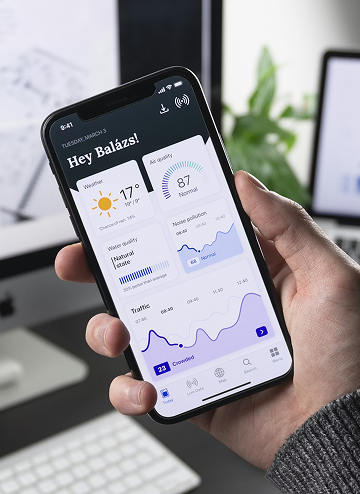 Hand holding smartphone displaying weather, air quality, noise, and traffic stats in a dashboard app.